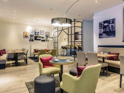 a restaurant with tables and chairs and a dining room at Mercure Hotel Hannover Mitte in Hannover