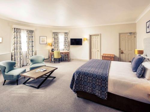 a hotel room with a bed and a table and chairs at Mercure Gloucester Bowden Hall Hotel in Gloucester
