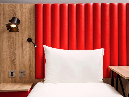 a red curtain in a bedroom with a bed at ibis Styles London Ealing in London
