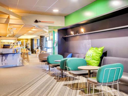 a waiting room with colorful chairs and tables at ibis Styles Paris Charles de Gaulle Airport in Roissy-en-France