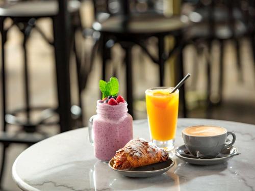 a table with a pink drink and a cup of orange juice at Novotel Surfers Paradise in Gold Coast