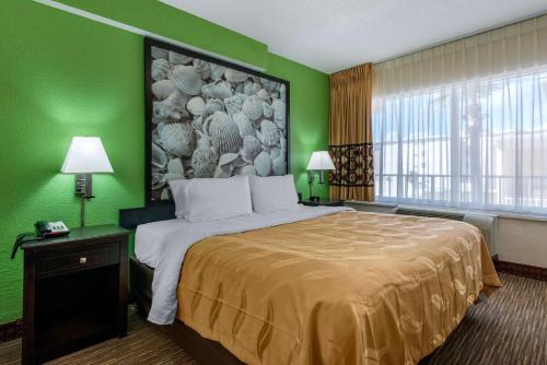 a hotel room with a large bed with a green wall at Quality Inn Daytona Beach Oceanfront in Daytona Beach