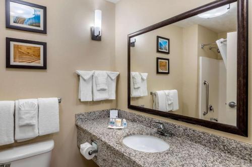 a bathroom with a sink and a large mirror at Comfort Suites Speedway - Kansas City in Kansas City