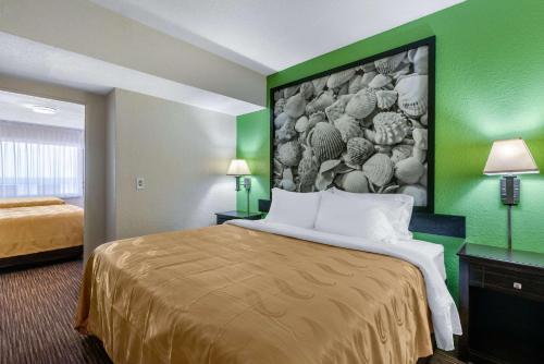 a hotel room with a bed with a painting on the wall at Quality Inn Daytona Beach Oceanfront in Daytona Beach