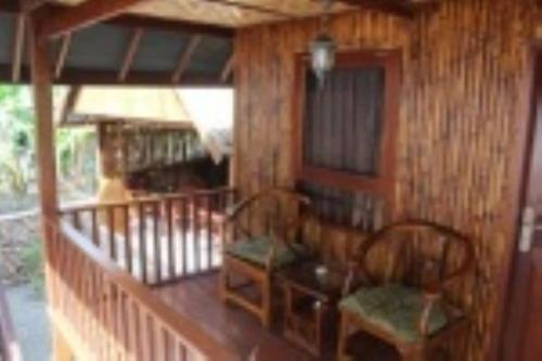 a wooden porch with two chairs and a table at Villa panrangluhu in Bira