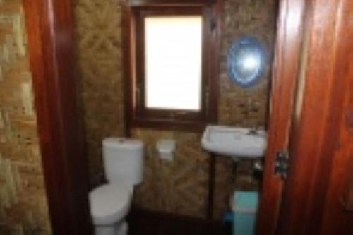a bathroom with a toilet and a sink and a window at Villa panrangluhu in Bira