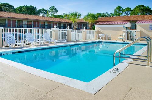 a large swimming pool with chairs and a fence at Rodeway Inn Panama City in Panama City