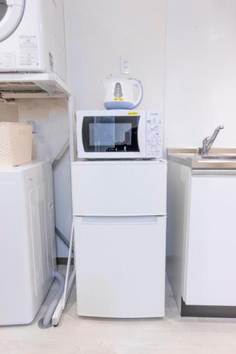 a white kitchen with a microwave and a sink at Hote Io Lite in Nago