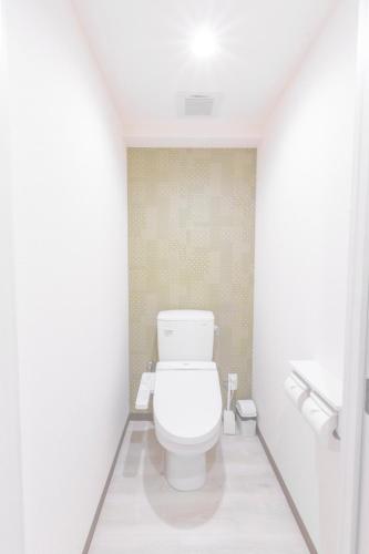 a bathroom with a white toilet in a room at Hote Io Lite in Nago