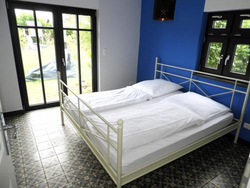 Ferienhaus mit Garten في غرال موريتز: سرير ابيض في غرفة بجدار ازرق