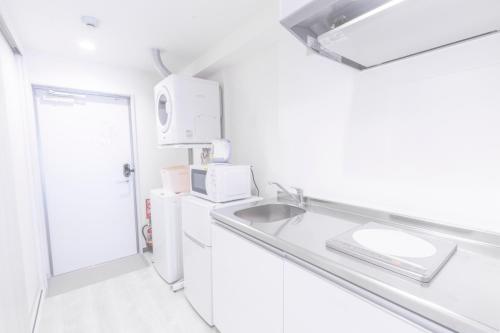 a white kitchen with a sink and a refrigerator at Hote Io Lite in Nago