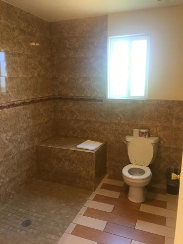 a bathroom with a toilet and a tub and a window at All 8 Motel in Long Beach
