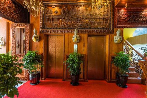 a hallway with potted plants on a red carpet at Okay Palace Hotel in Phnom Penh