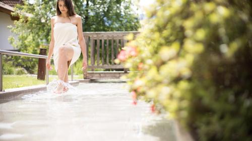 a woman in a white dress walking in the water at Biohotel theiner's garten in Lana