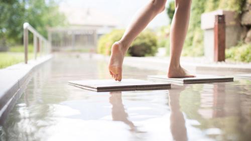 a person standing on a pool with their feet on the water at Biohotel theiner's garten in Lana