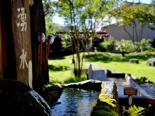 a water feature in a garden with a stream at Tabinoyado Asonoyu in Aso