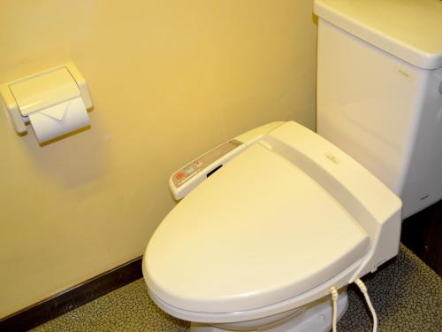 a white toilet in a bathroom with a roll of toilet paper at Tabinoyado Asonoyu in Aso