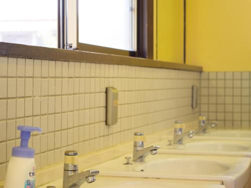 a public bathroom with three sinks and a mirror at Tabinoyado Asonoyu in Aso