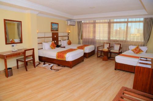 ein Hotelzimmer mit 2 Betten und einem Schreibtisch in der Unterkunft Tiffany Diamond Hotels Ltd - Indira Gandhi street in Daressalam