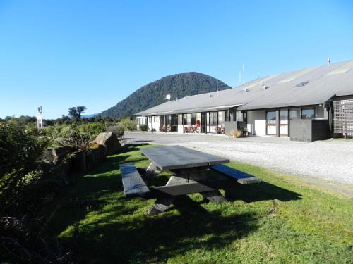 a picnic table sitting in the grass in front of a building at ASURE Aspiring Court Motel in Haast