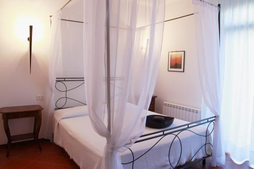 a bedroom with a white canopy bed with a window at Elba Vip in Porto Azzurro