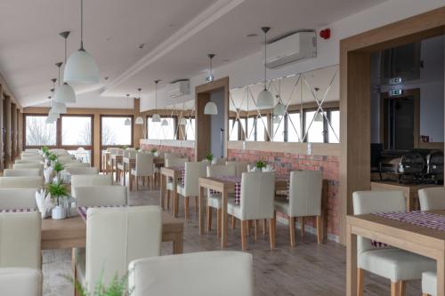 un restaurante con mesas blancas y sillas blancas en Przystanek Alaska, en Zieleniec