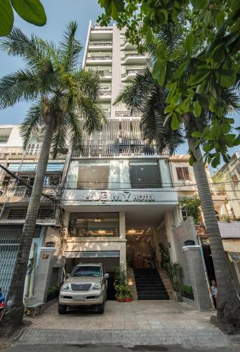 a car parked in front of a building with palm trees at Hue My Hotel in Ho Chi Minh City