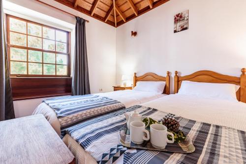 Duas camas num quarto com uma bandeja com canecas em EL MIRADOR em Puntagorda