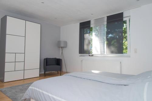 a white bedroom with a bed and a window at Location 1 in Rimschweiler