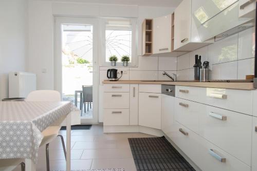 a kitchen with white cabinets and a dining table at Location 1 in Rimschweiler