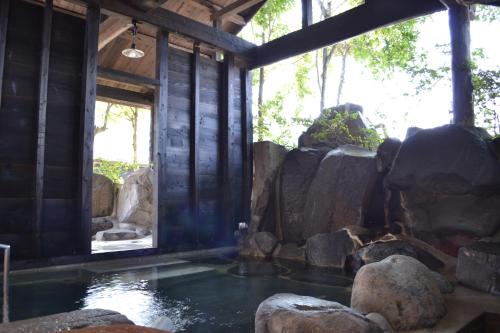 a room with a pool of water and rocks at Tabinoyado Asonoyu in Aso