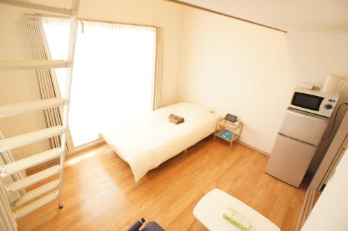 um pequeno quarto com uma cama e um frigorífico em Plusone Fujisaki em Fukuoka