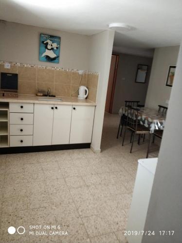 a kitchen with white cabinets and a dining room with a table at Didi Guest House in Bet Sheʼan