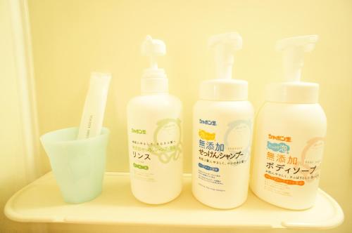 a group of four bottles and a cup on a shelf at Plusone Fujisaki in Fukuoka