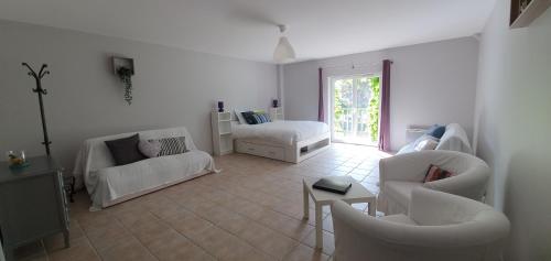 a living room with white furniture and a window at Domaine des Pêcheries in Montel-de-Gelat