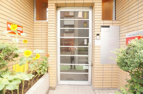 a white door on a house with flowers at Plusone Fujisaki in Fukuoka
