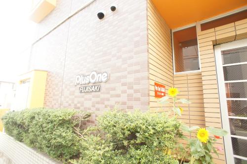 a building with a sign on the side of it at Plusone Fujisaki in Fukuoka