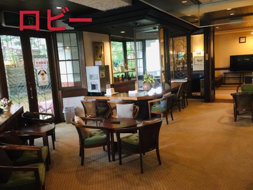 茅野的住宿－白樺湖榮園，餐厅设有木桌、椅子和窗户。