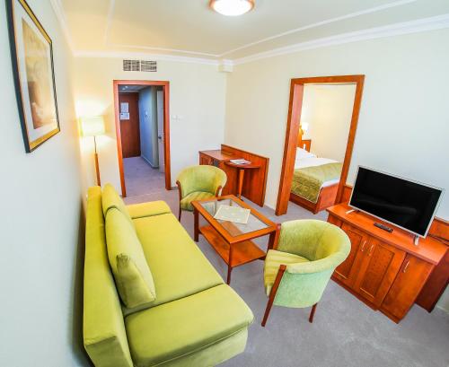 a living room with a couch and a television and a bed at Hotel Silver in Hajdúszoboszló