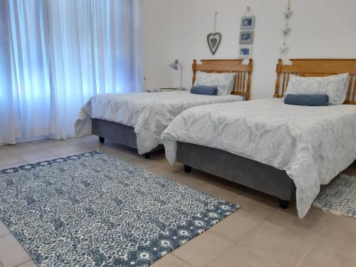 1 dormitorio con 2 camas y alfombra en Lieflappie❤, en Stilbaai