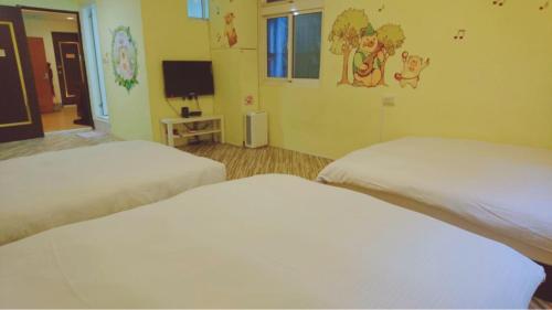 a room with two beds and a tv in it at Fengjia Love I Hostel in Taichung
