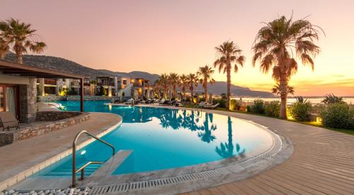 a pool at a resort with palm trees at Ikaros Beach, Luxury Resort & Spa in Malia