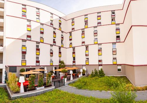 an exterior view of a building with tables and umbrellas at Apparthotel Privilodges Carré de Jaude in Clermont-Ferrand
