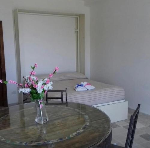 a room with a table and a bed with a vase of flowers at Dimora dei Cardinali in Agropoli