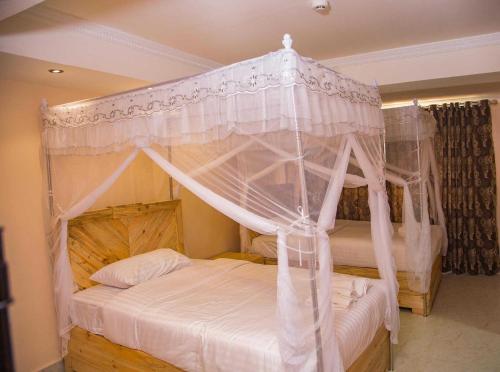 1 dormitorio con cama con dosel y cortinas blancas en Emmaus Guesthouse Kampala, en Kampala