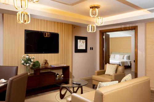 a living room with a couch and a tv in a hotel room at Best Western Plus Metro Clark in Angeles