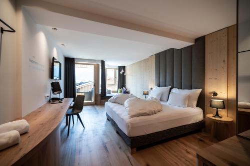 um quarto com uma cama grande e uma secretária. em Hotel Simpaty em Dobbiaco