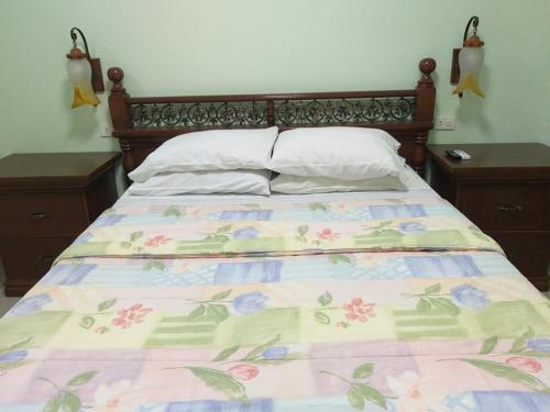 a bed with a floral bedspread and two night stands at Dweller's Pensione in Iloilo City