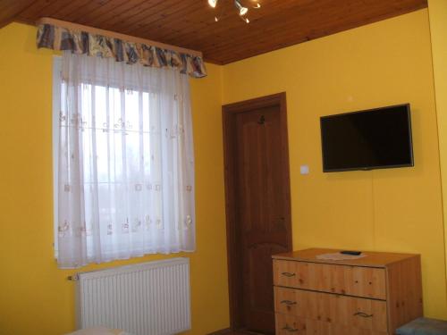 デブレツェンにあるTó Vendégházのベッドルーム(テレビ付)、窓付きドレッサーが備わります。