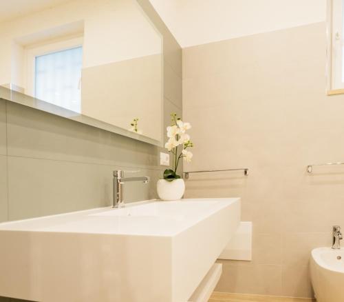 a white bathroom with a sink and a vase of flowers at Golden Residence in Caianello